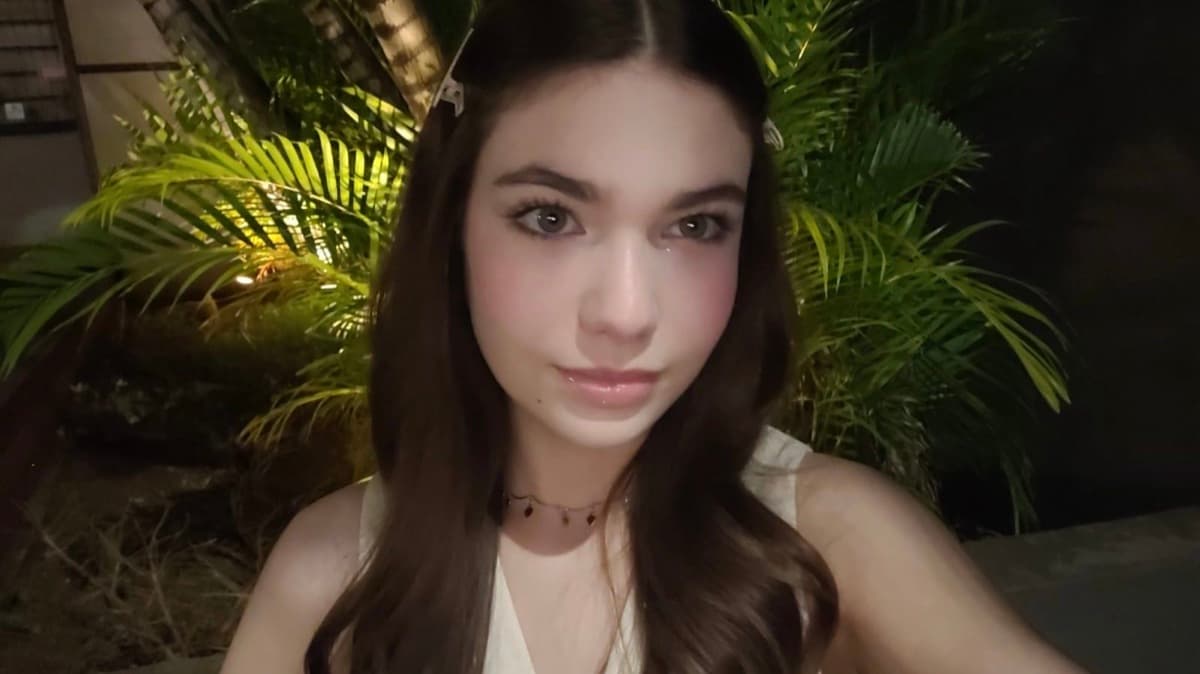 Isabella Oliveira Amorim in front of palm leaves at night